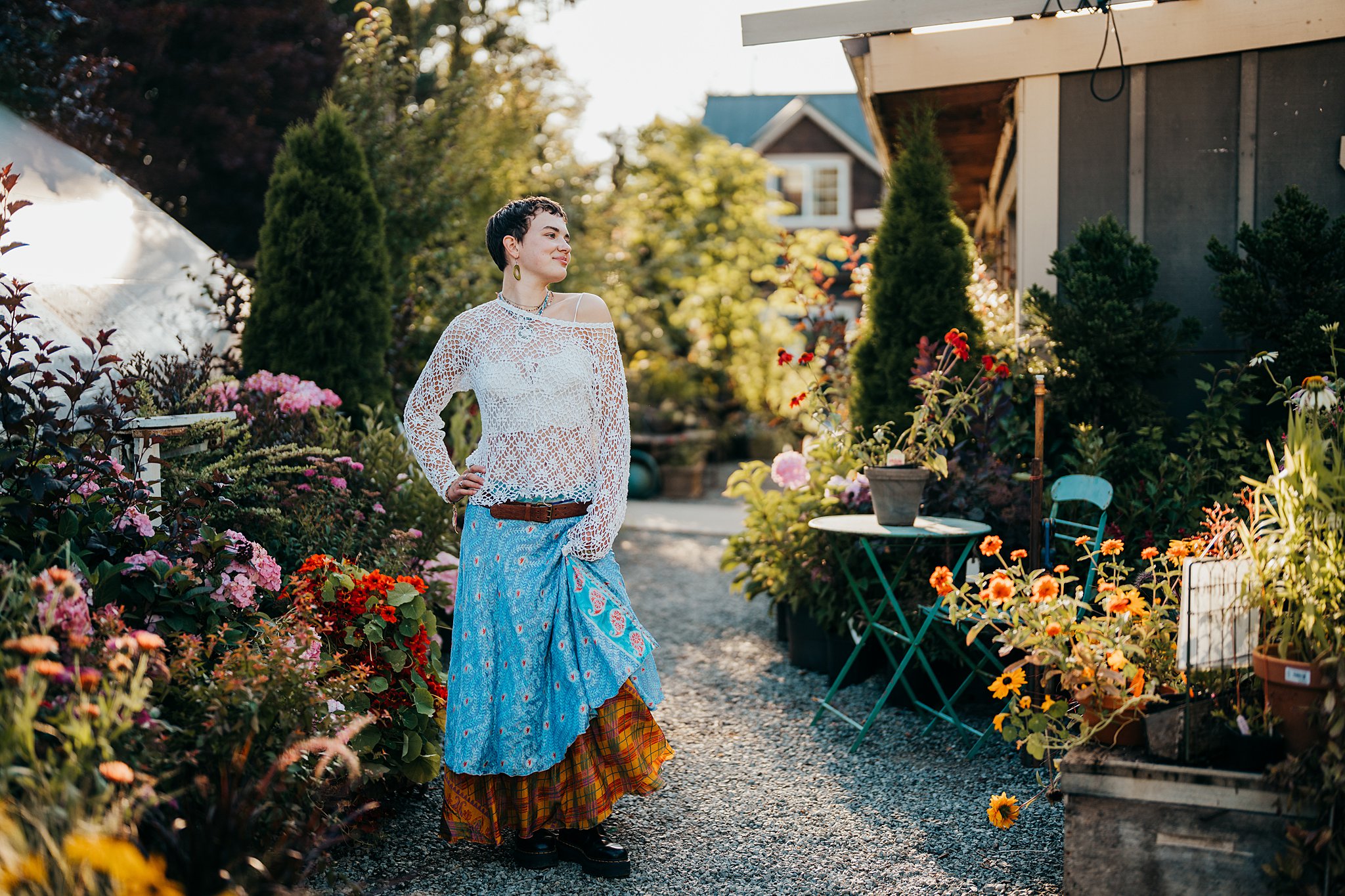 A woman in a white top and colorful skirt stands in a garden path surrounded by flowers while holding her skirt Seattle Photoshoot Locations