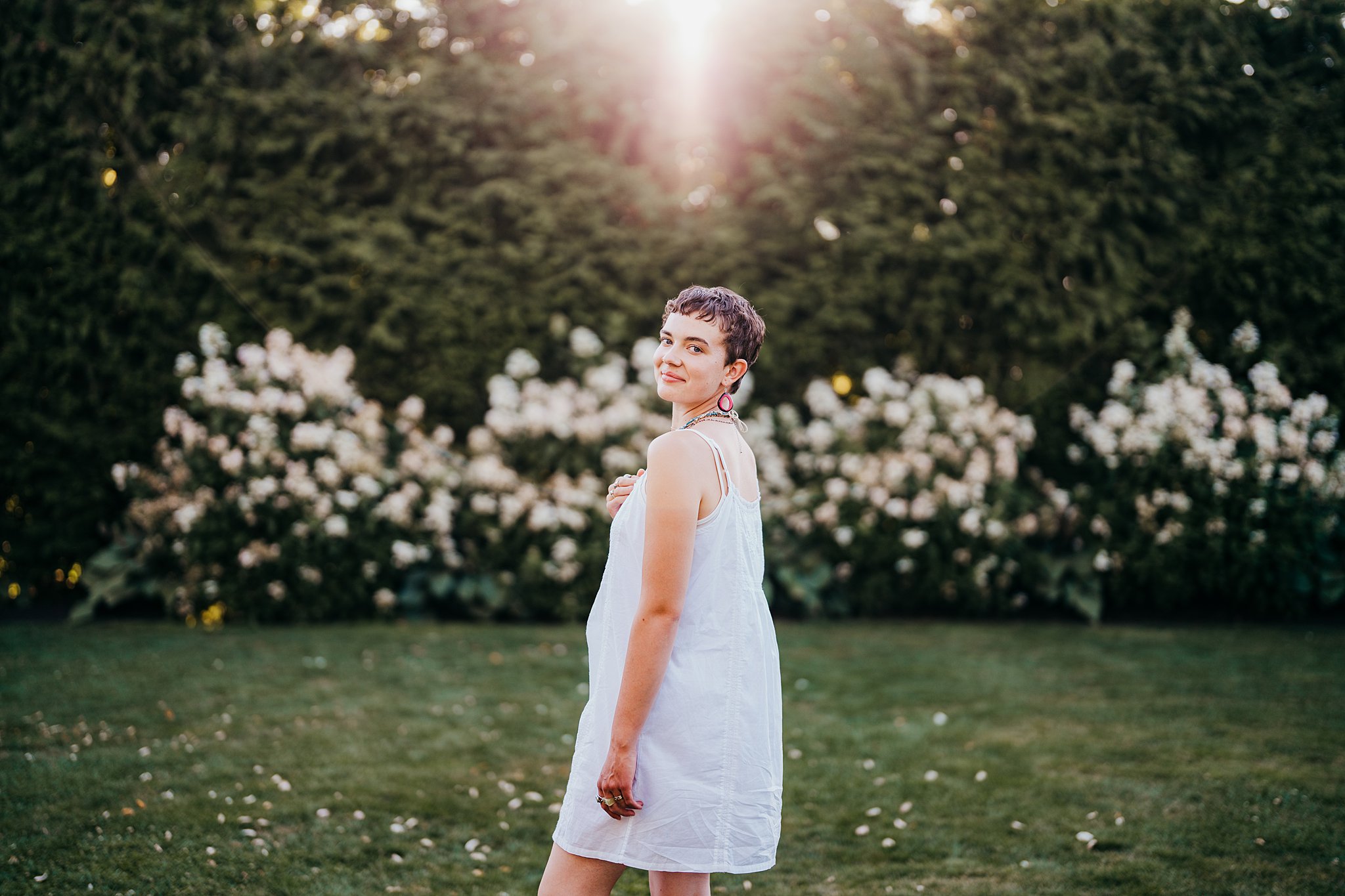 A woman in a white dress looks over her shoulder while walking through a garden of white flowers Seattle Photoshoot Locations