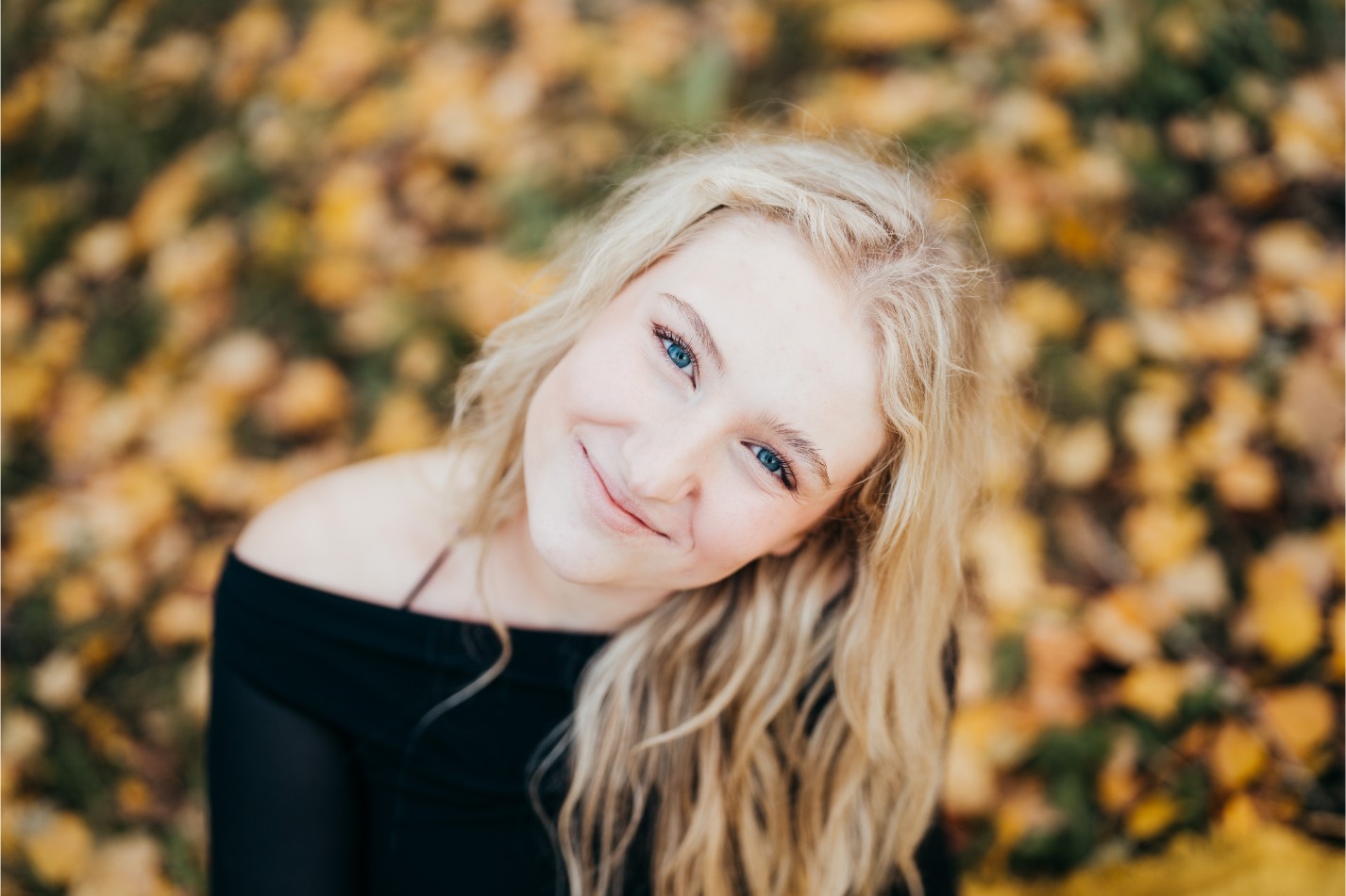 a senior girl portrait with yellow leaves as the background smiling to the camera at luther burbank park on mercer island