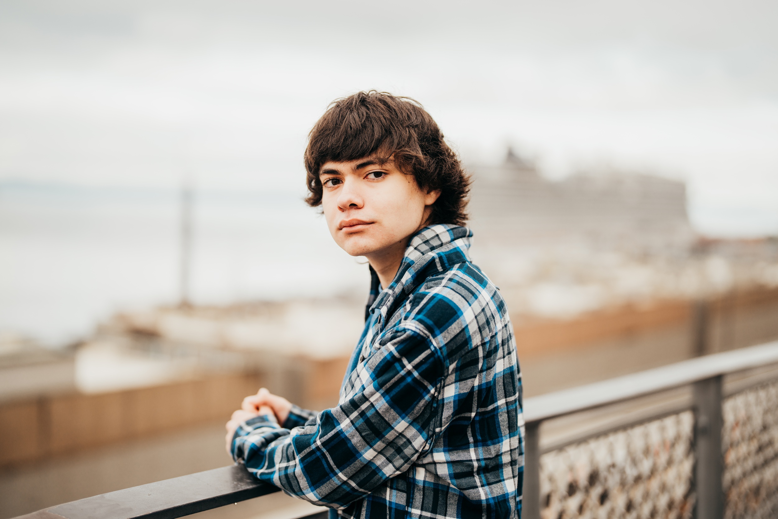 A Ballard High School senior looks over his shoulder while leaning on a railing by the water