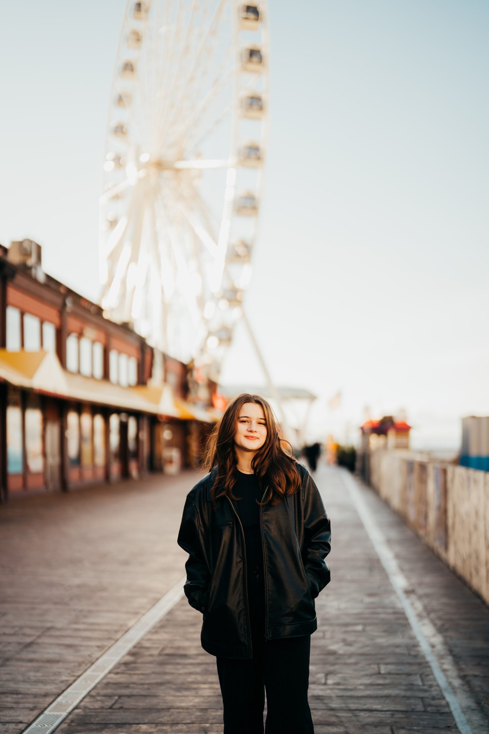 A Bellevue High School senior girl in a black jacket walk on the pier smiling at sunrise