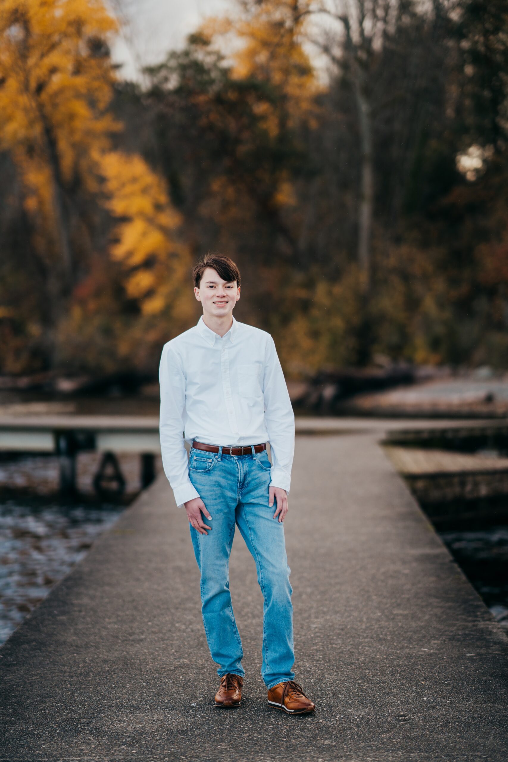 A Garfield High School senior in a white shirt and jeans walks on a concrete dock in fall