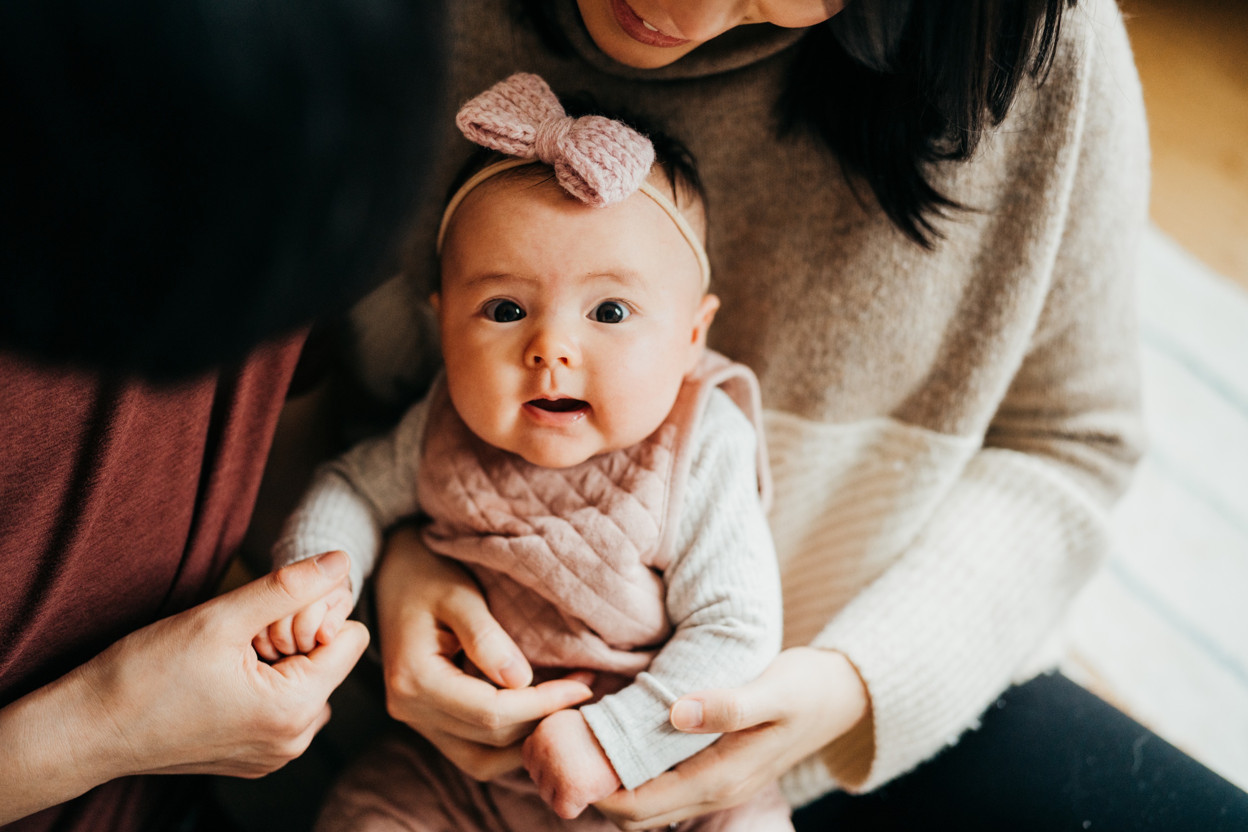 A happy newborn sits in mom's lap while holding hand dad's hand after visiting baby boutiques in seattle