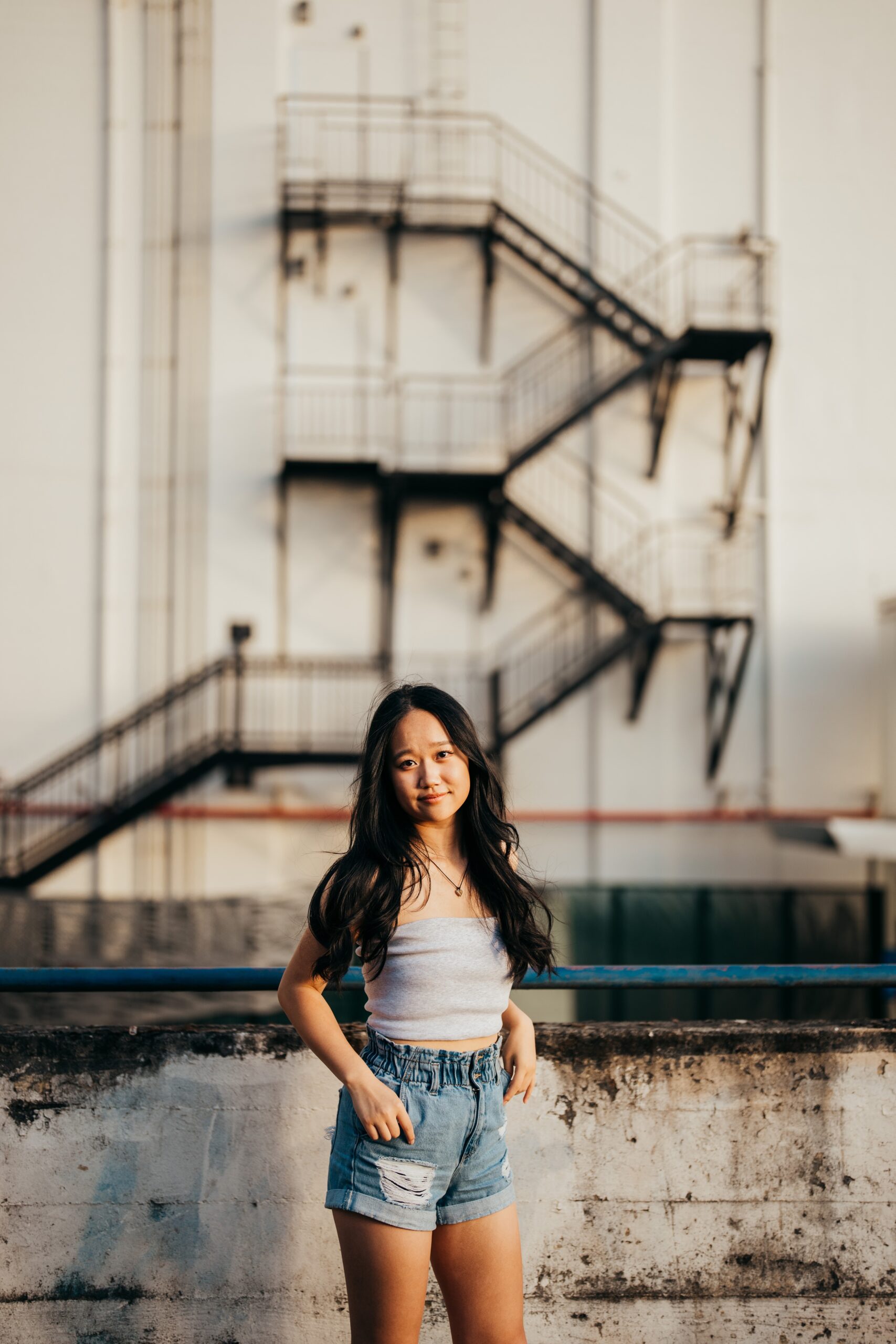 A high school senior in a grey top and jean shorts stands in an alley after exploring boutiques in seattle