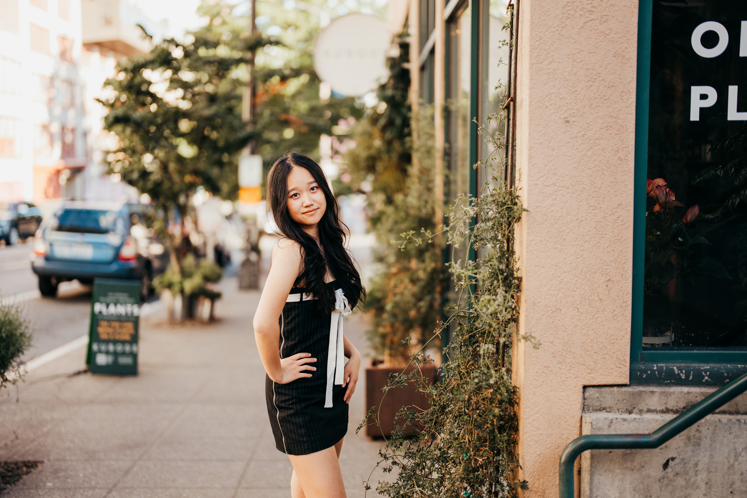 A teenage girl in a black dress walks in a downtown sidewalk while exploring boutiques in seattle