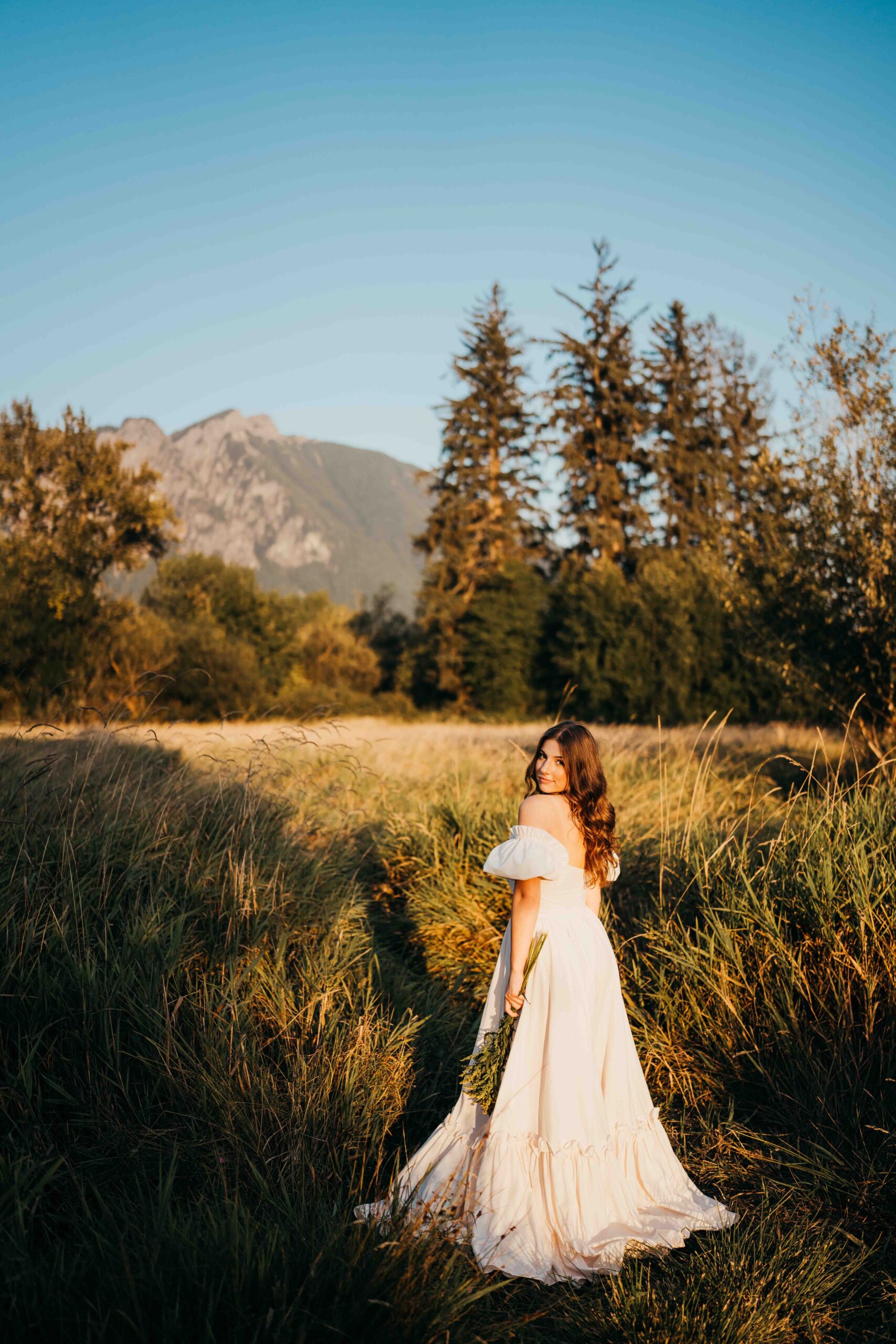 A high school senior looks over her shoulder in a white gown after finding homecoming dresses in seattle