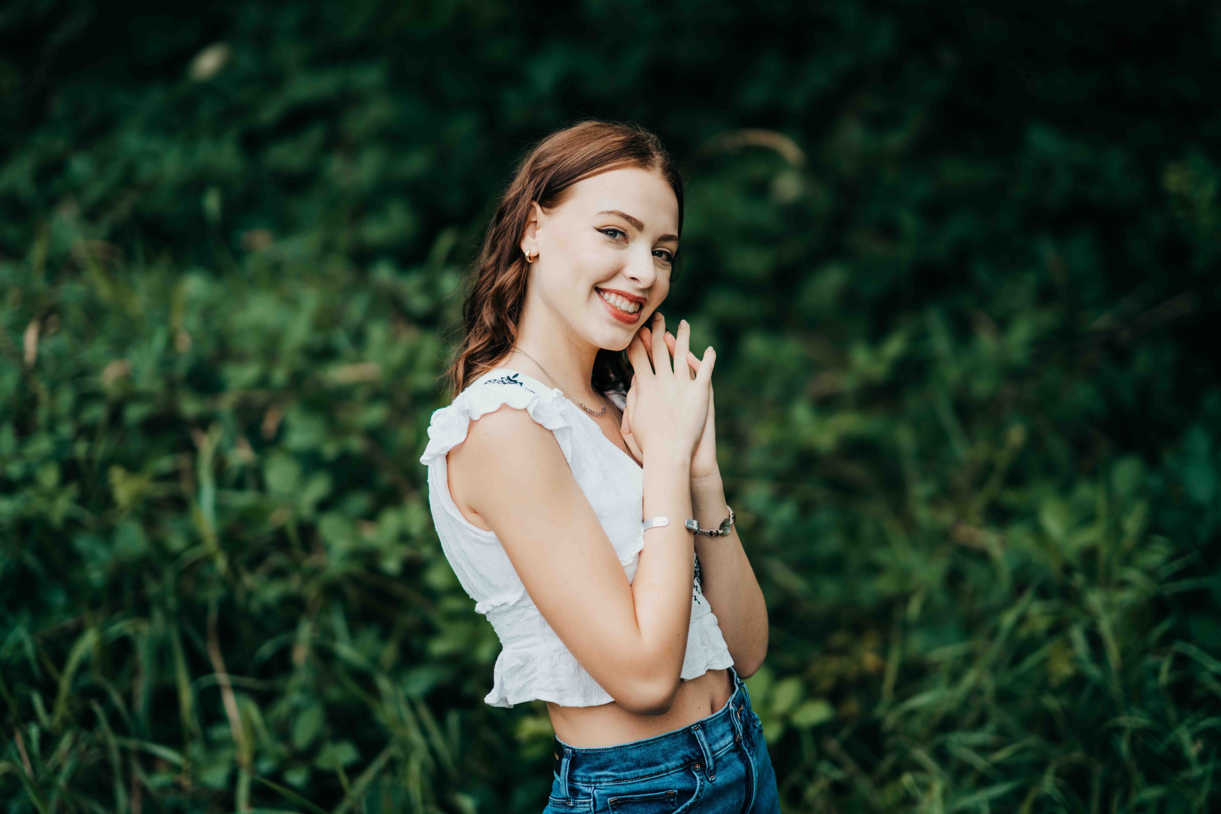 A happy high school sneior explores a park with a big smile