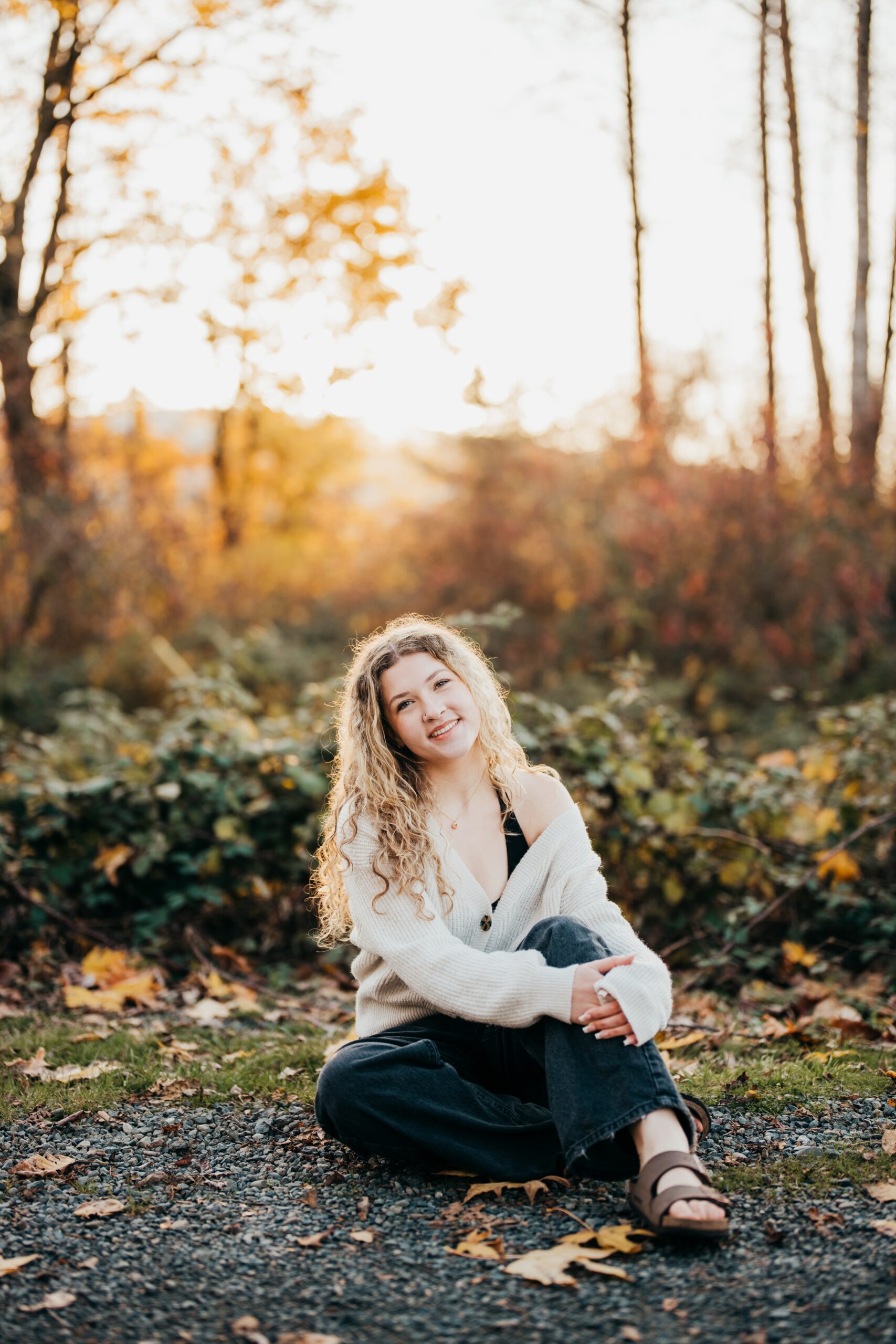 A graduate sits in the trail of a park at sunset