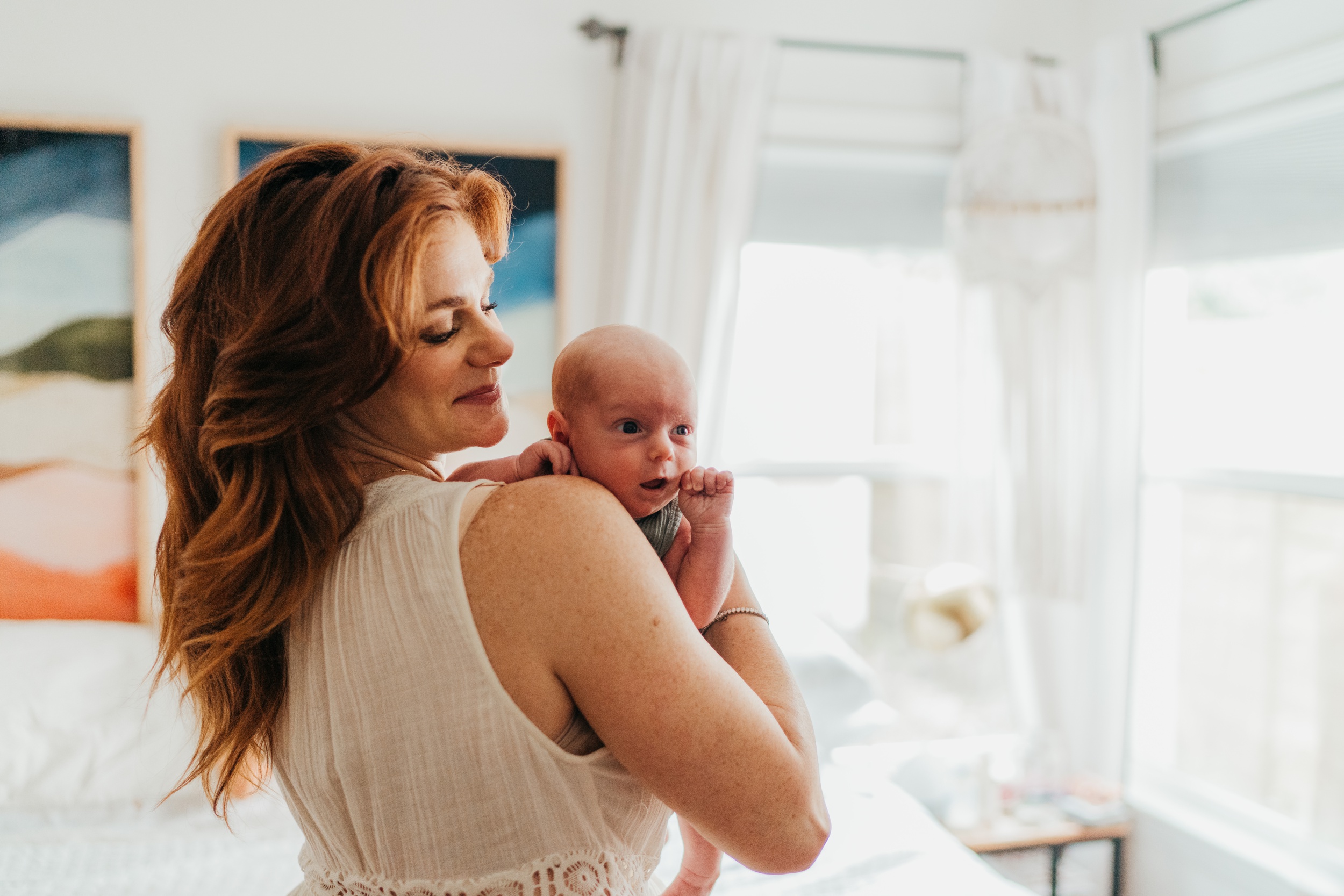 A happy new mom holds her newborn in a bedroom after using northshore midwives