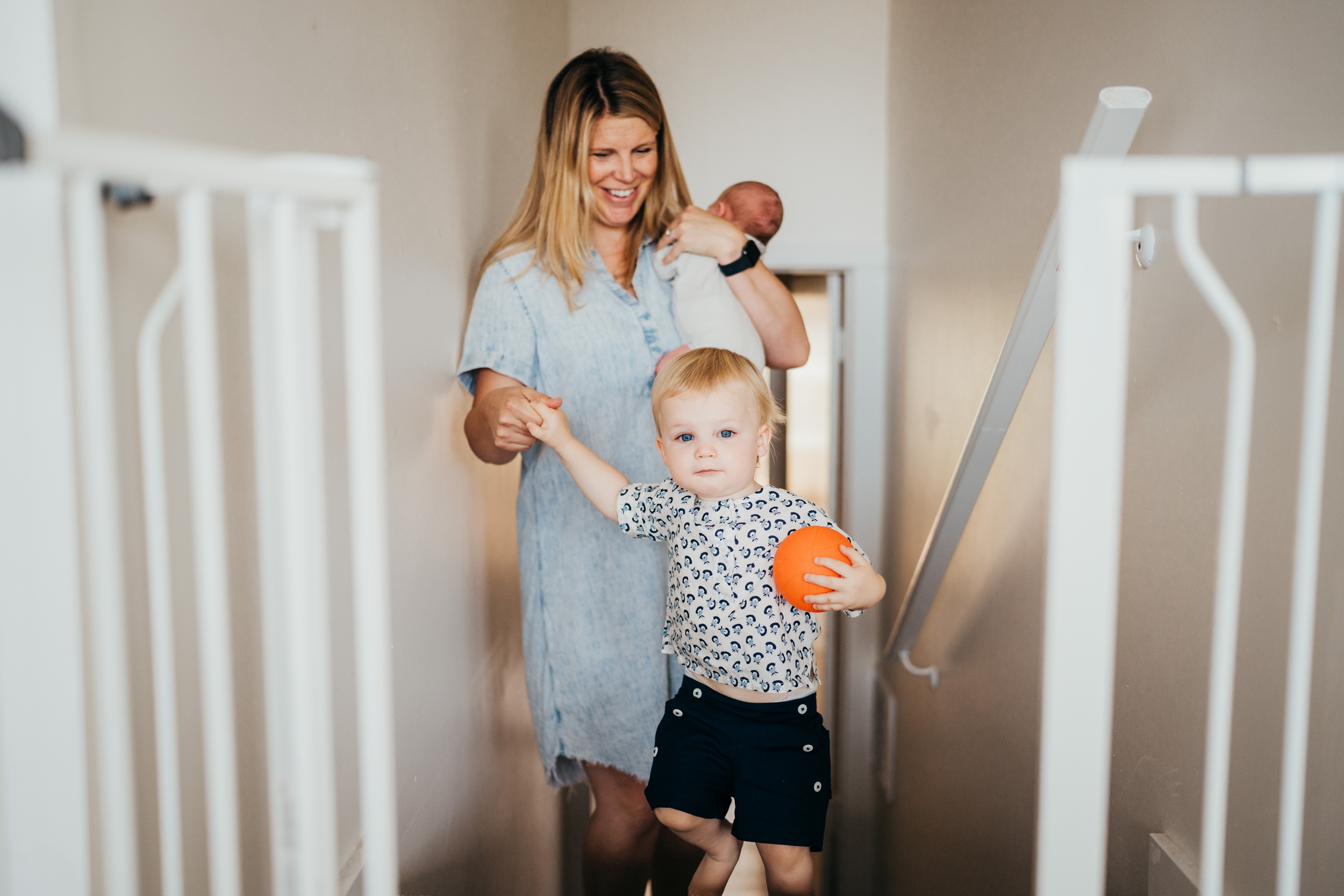 A toddler holding a ball leads mom up the stairs by the hand after visiting pediatric dentists in mercer island
