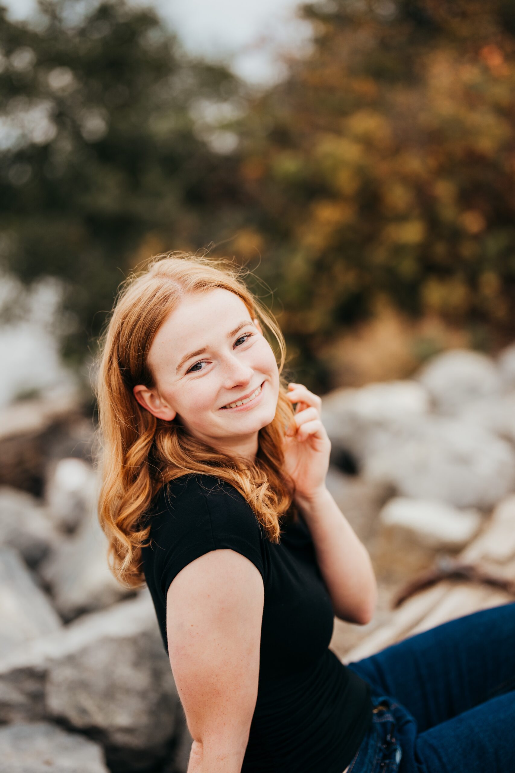 A happy teenage girl sits on rocks smiling in a black shirt after attending private high schools seattle