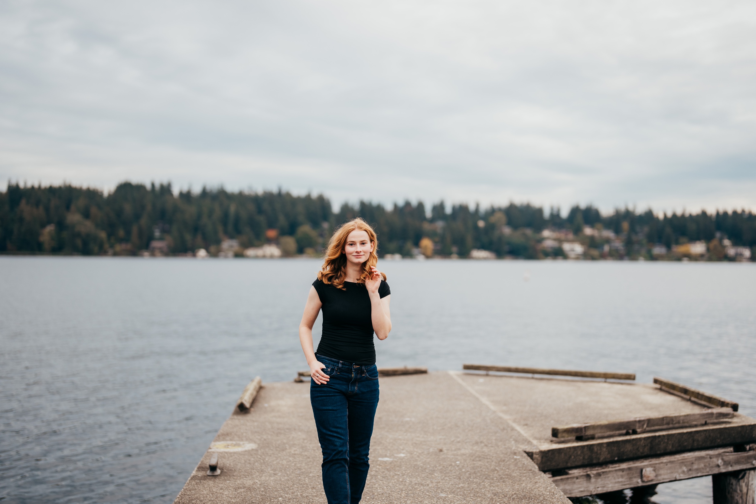 A high school senior walks on a dock in a black shirt and jeans after attending private high schools seattle