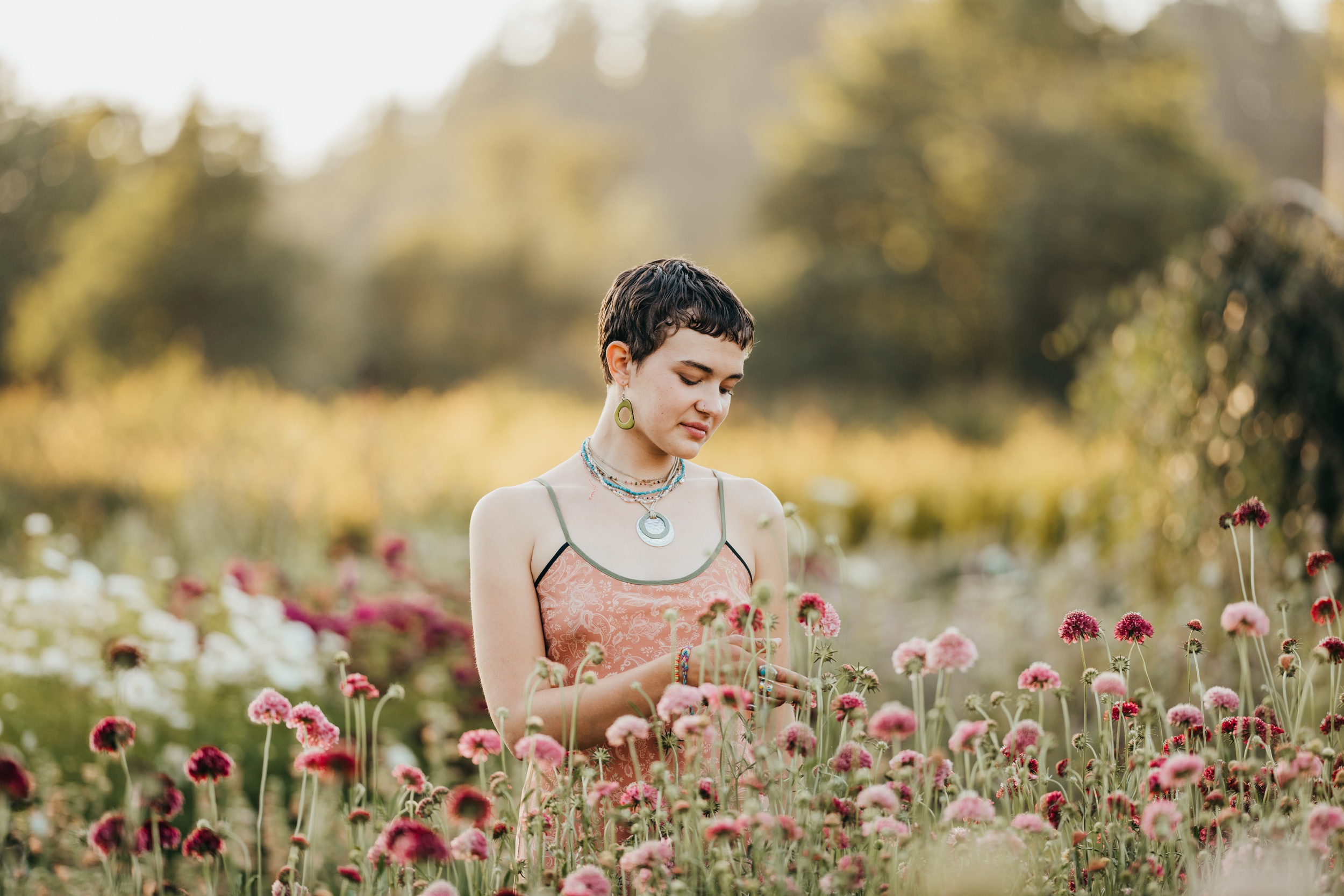 A high school senior in a pink tank top explores a field of wildflowers at sunset after some sat prep on mercer island