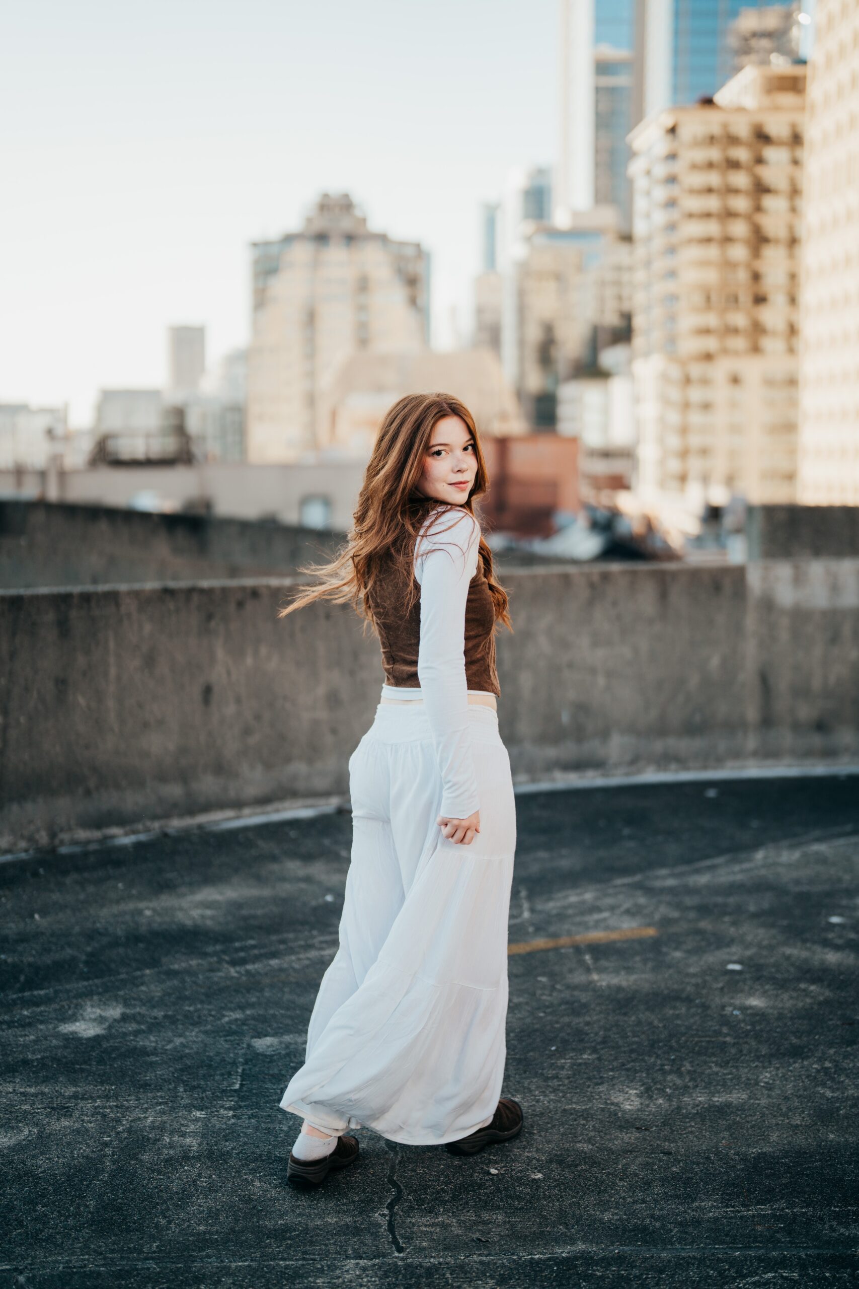 A high school senior in a white dress walks on a rooftop in downtown after finding tutoring in seattle