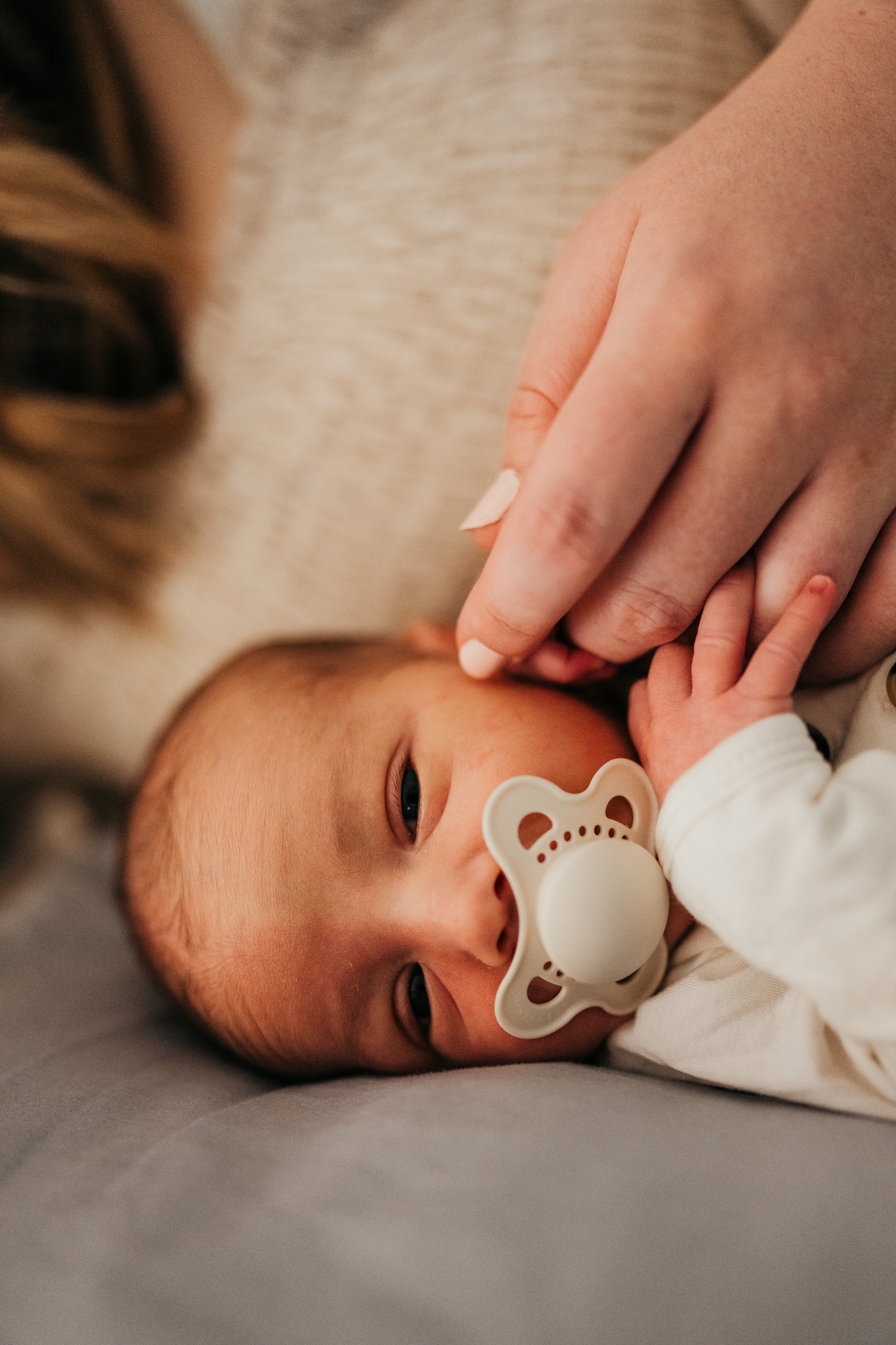 Details of a newborn baby holding mom's finger on a bed after using baby shower venues in seattle