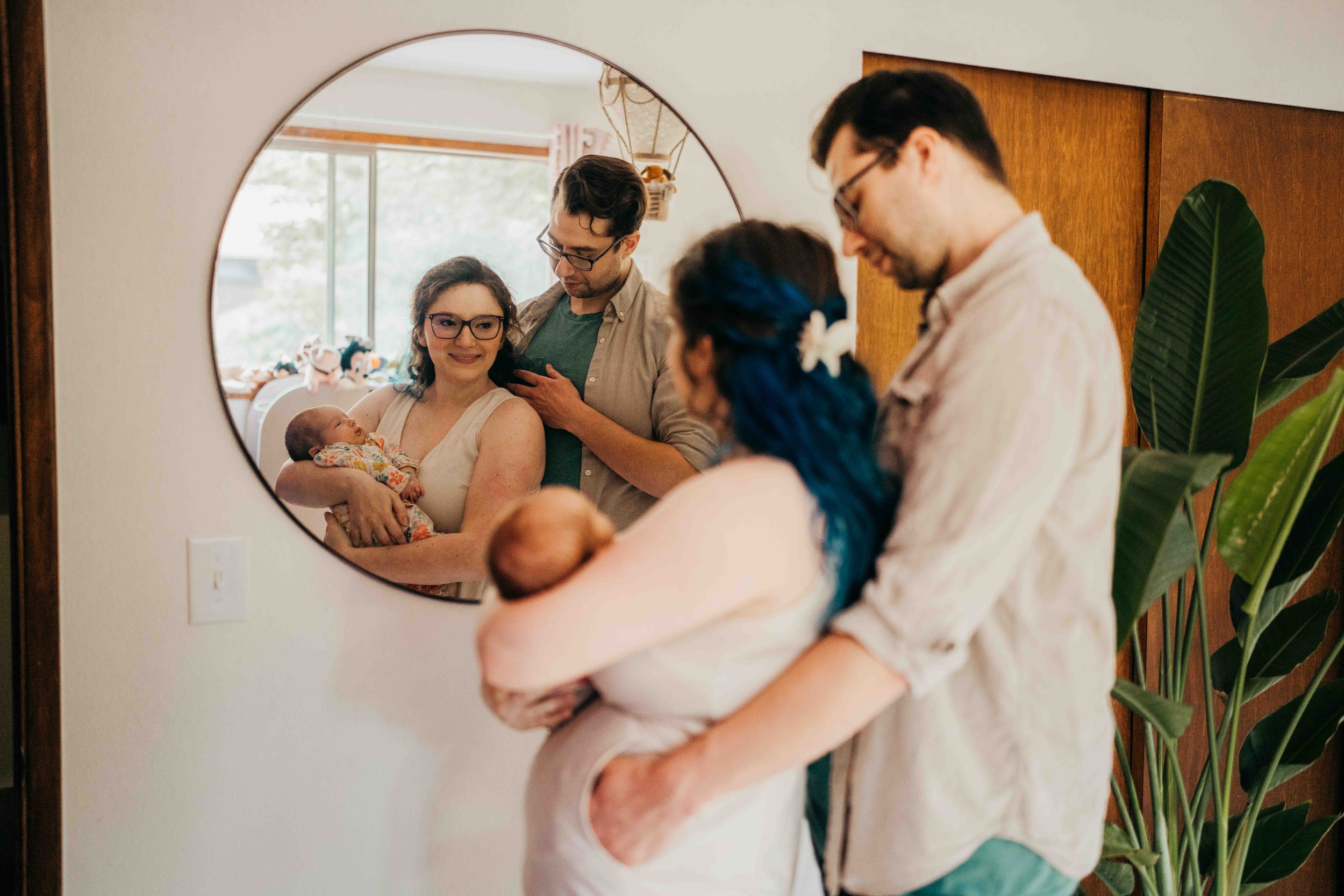 Happy new parents cuddle while holding their newborn daughter in a mirror before visiting fit4mom seattle