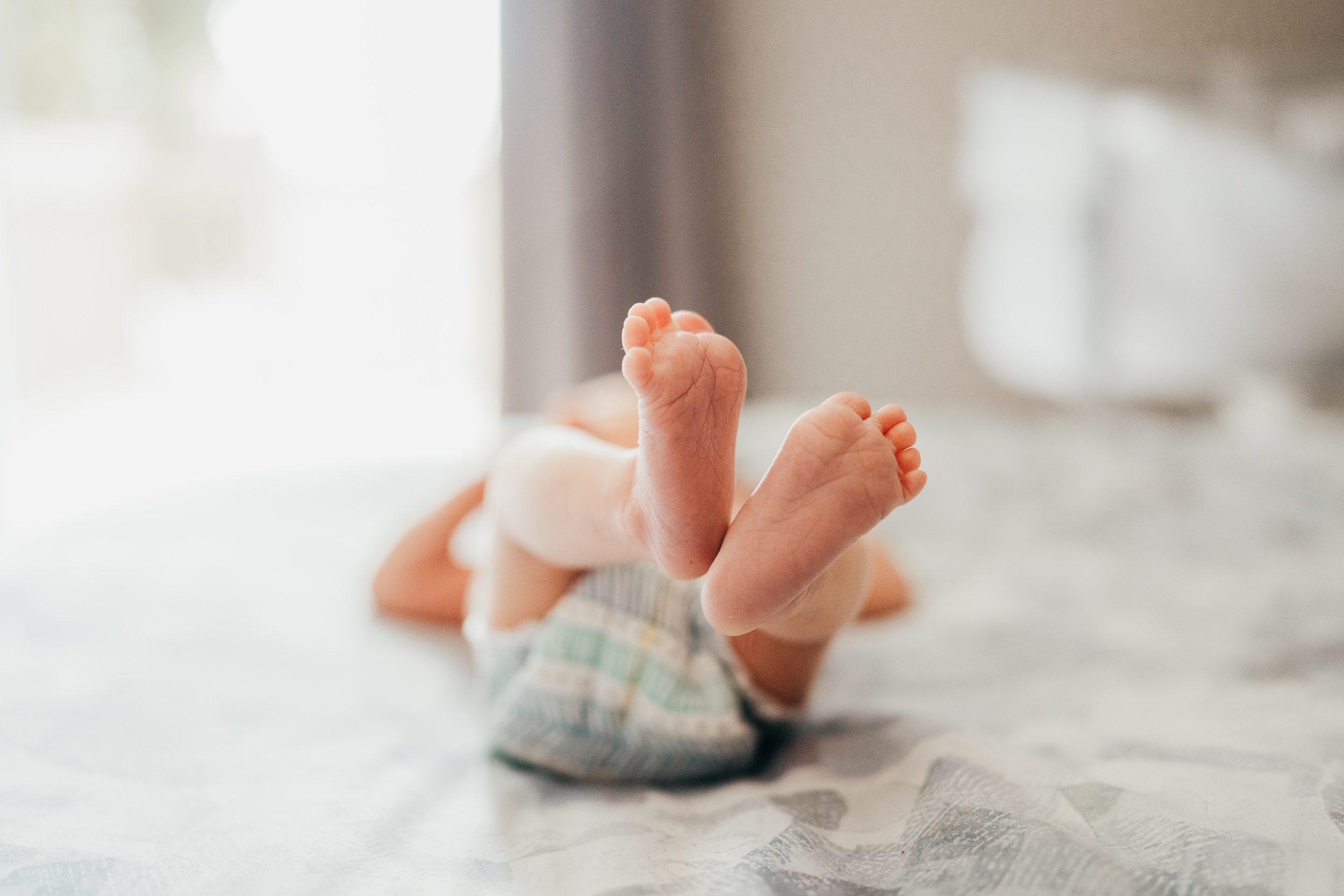 Details of a newborn baby's feet on a bed in a diaper after an infant massage in seattle