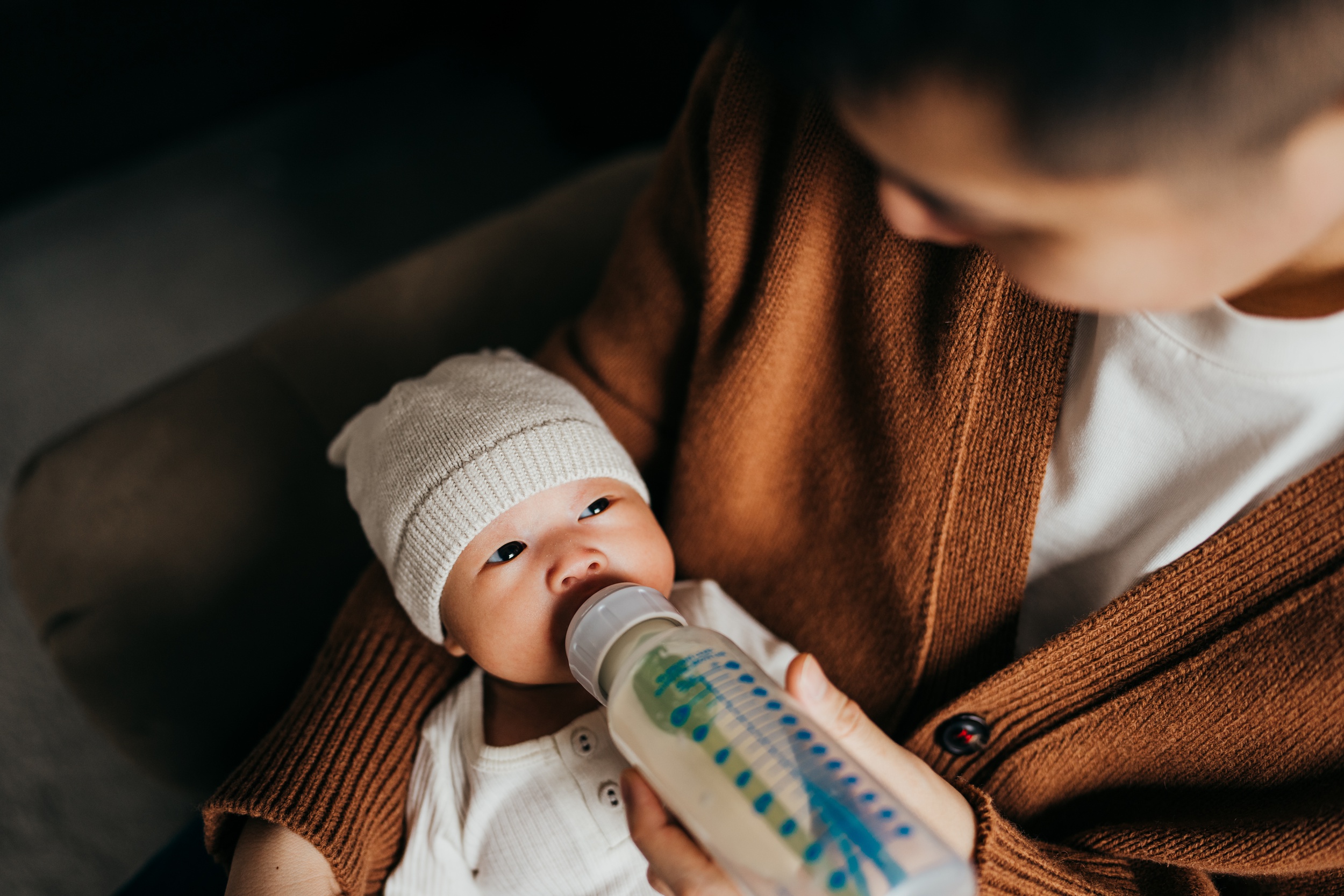 A newborn bottle feeds in dad's lap thanks to support from maternal fetal medicine in seattle