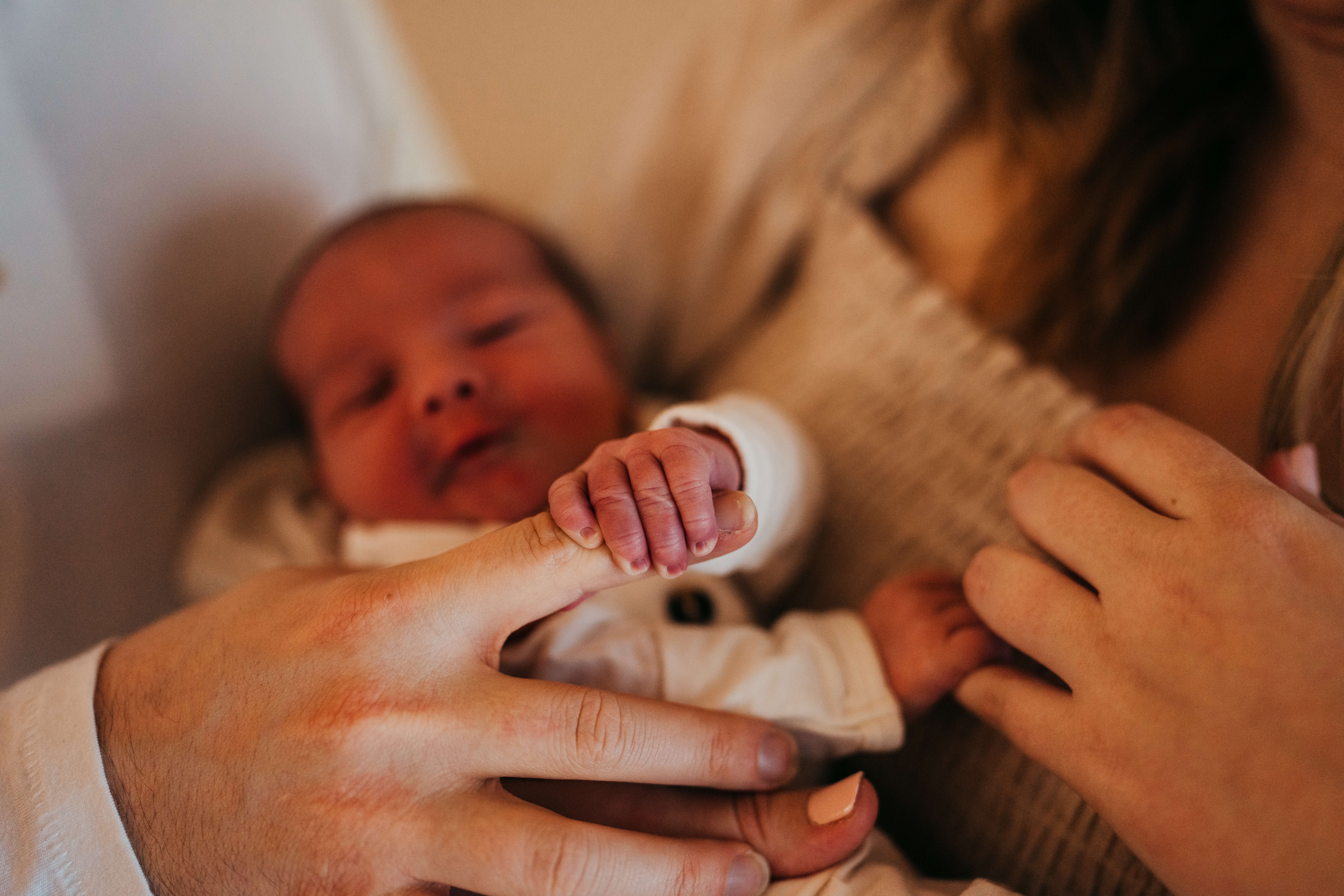 Details of a newborn's hand holding dad's finger thanks to fertility specialists in seattle