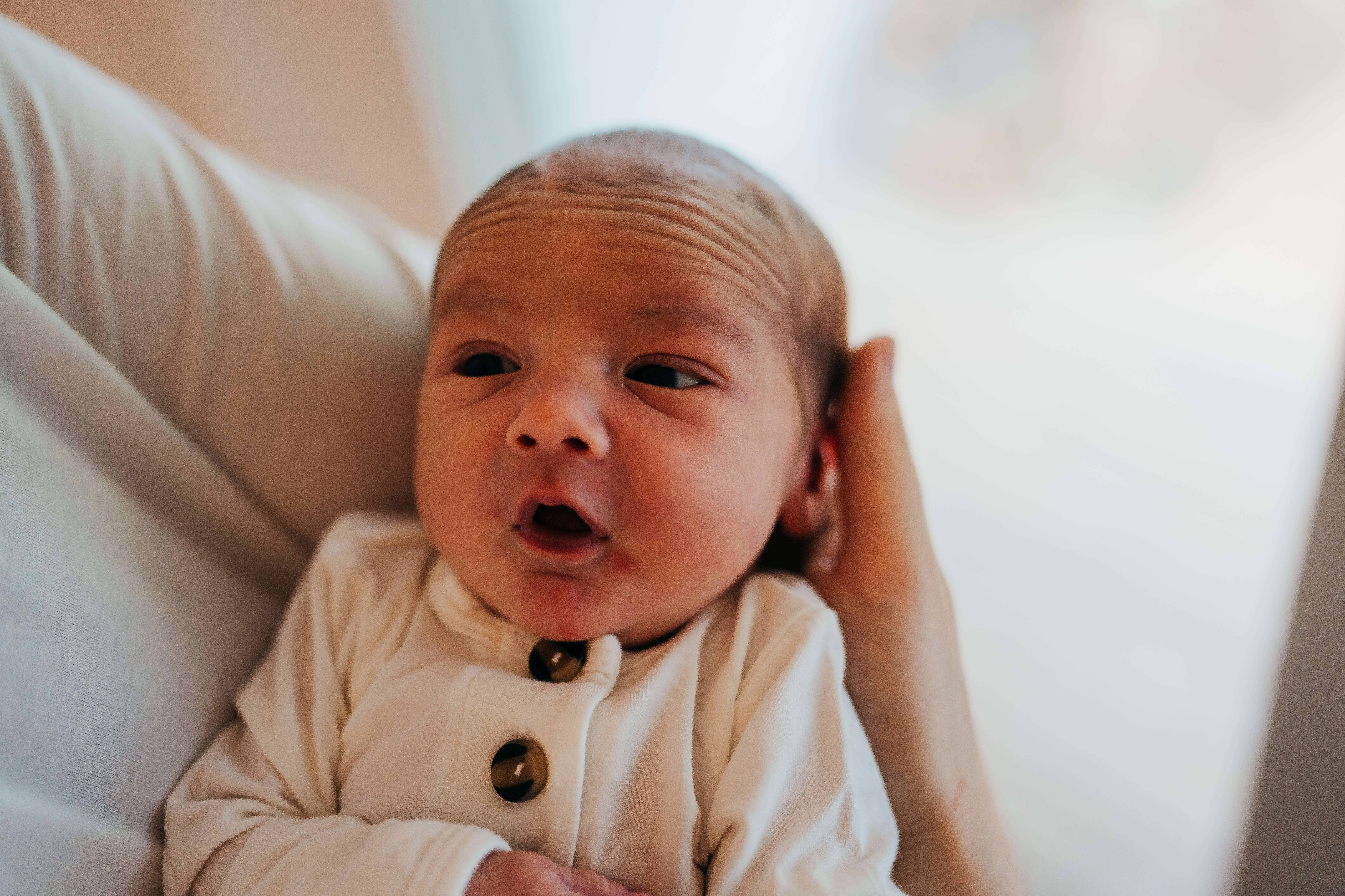 A newborn looks up from dad's arms in a white onesie thanks to fertility specialists in seattle