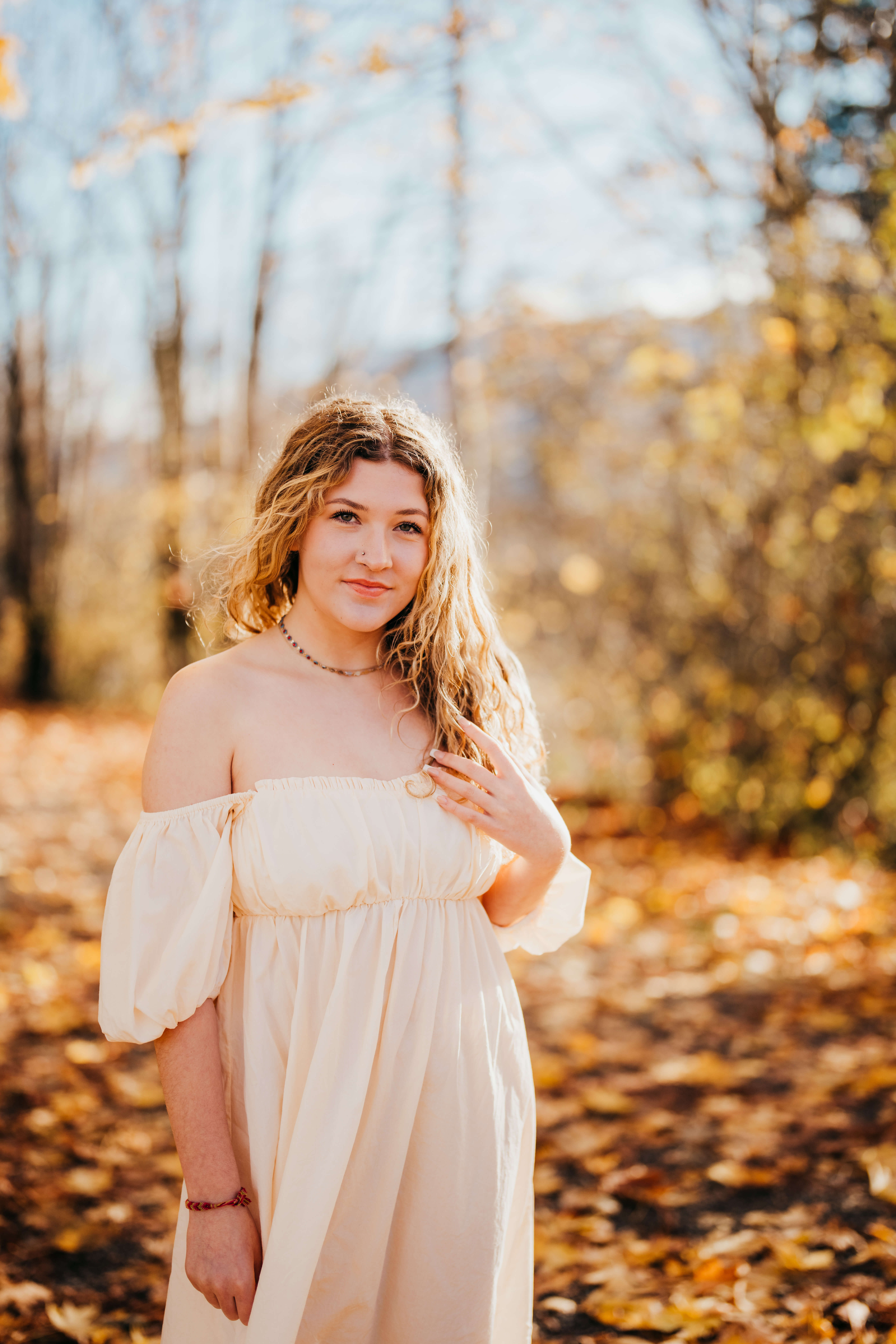 A high school senior in a white dress walks in a forest at sunset smiling after using Running Start Program In Seattle