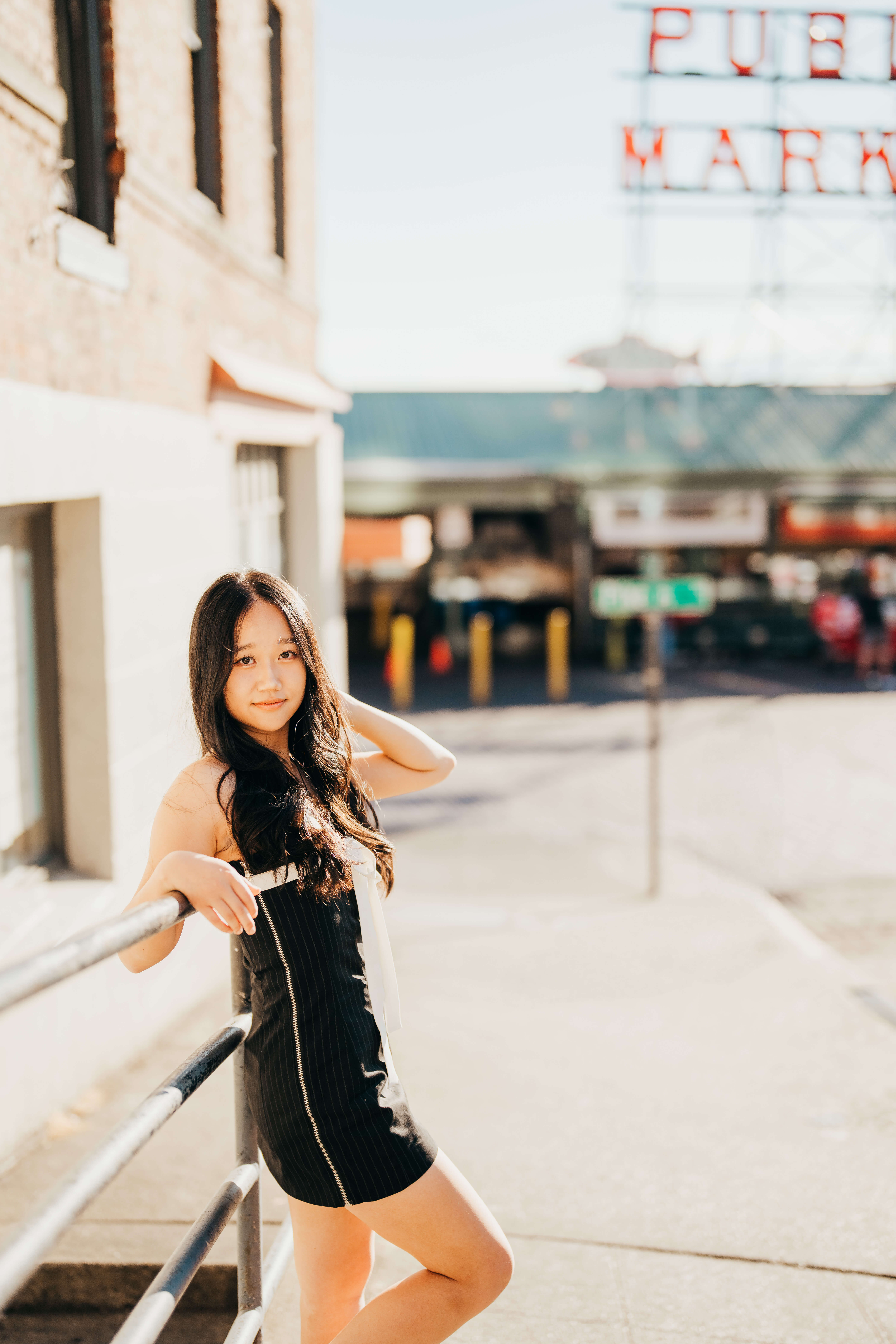 A high school senior leans on a railing in front of the Seattle market