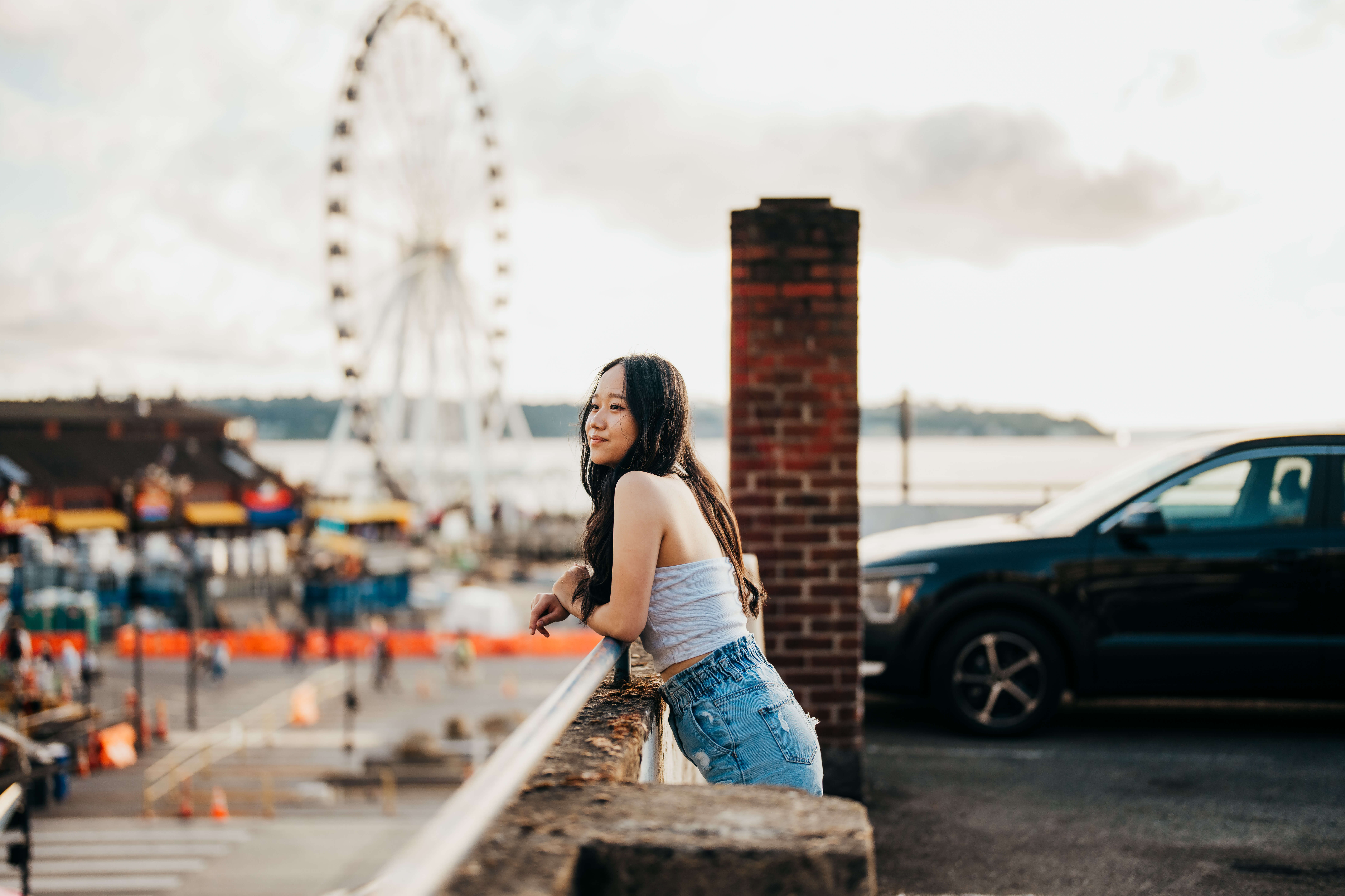 A high school senior leans on the top of a parking garage overlooking the ferris wheel after finding scholarships in seattle
