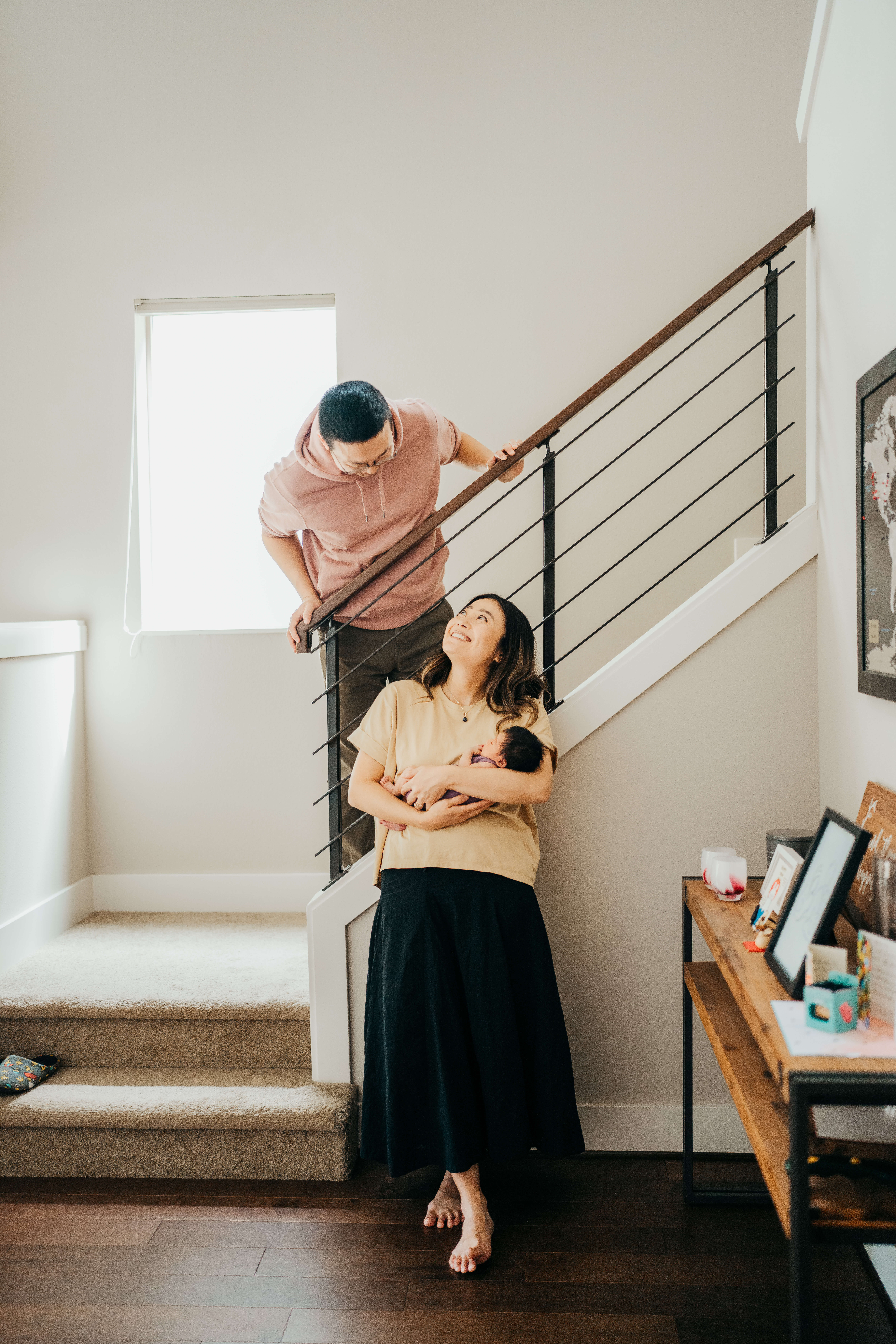 New mom and dad lean on the stairs while holding a newborn before exploring date night ideas in seattle