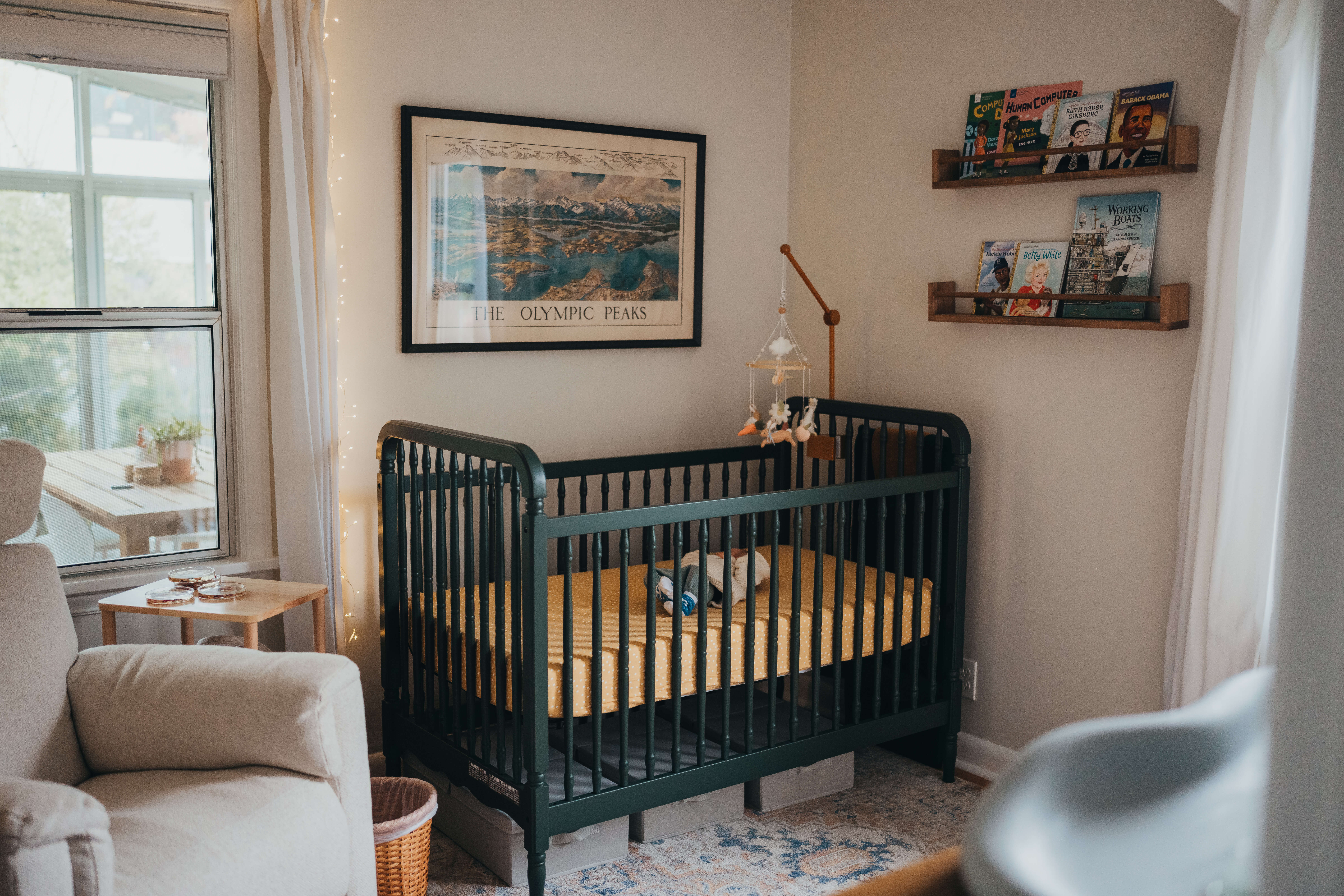 Details of a newborn baby's nursery with dark crib and bookshelves
