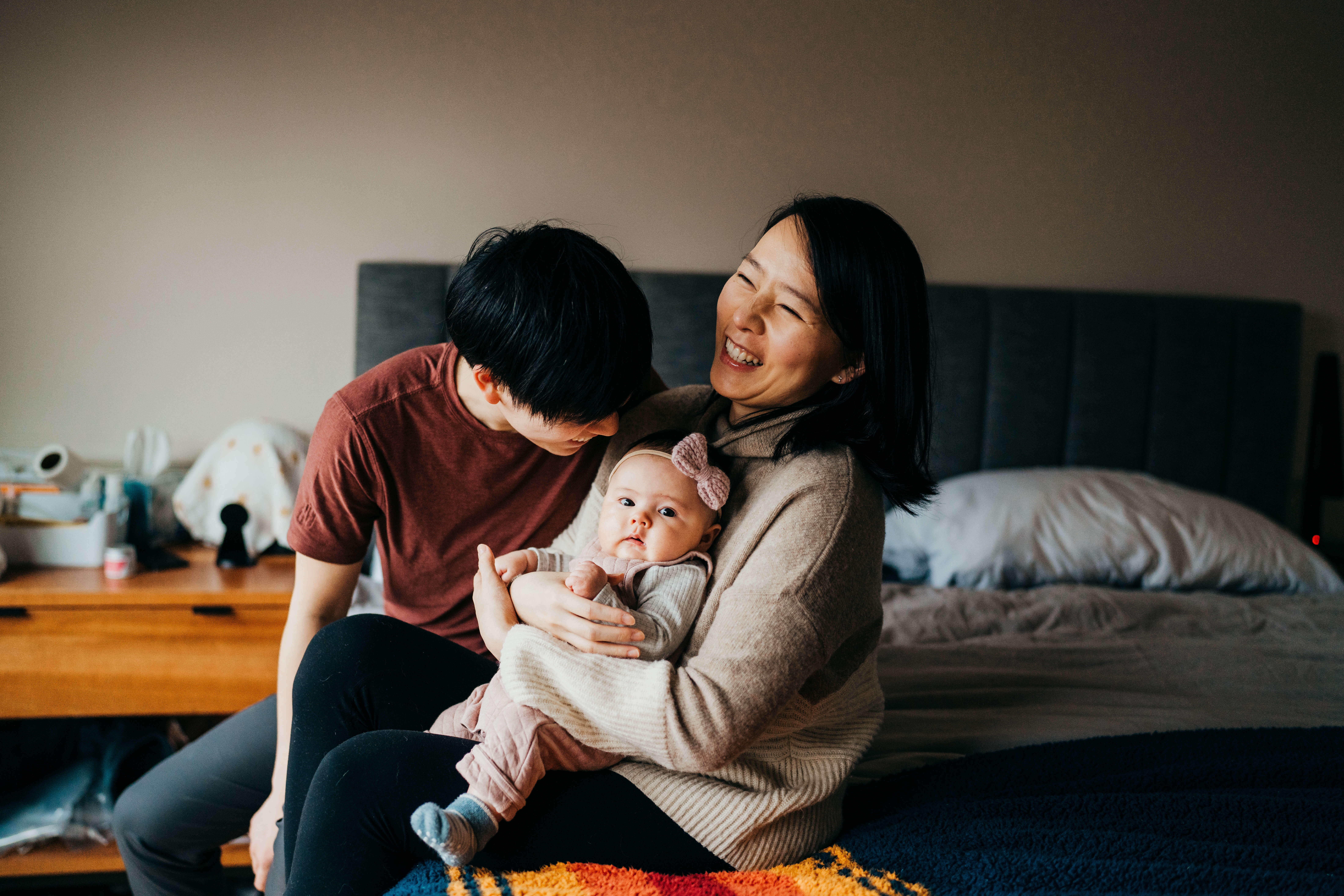 A new mom and dad laugh while holding their baby and sitting on a couch thanks to seattle children's fetal center