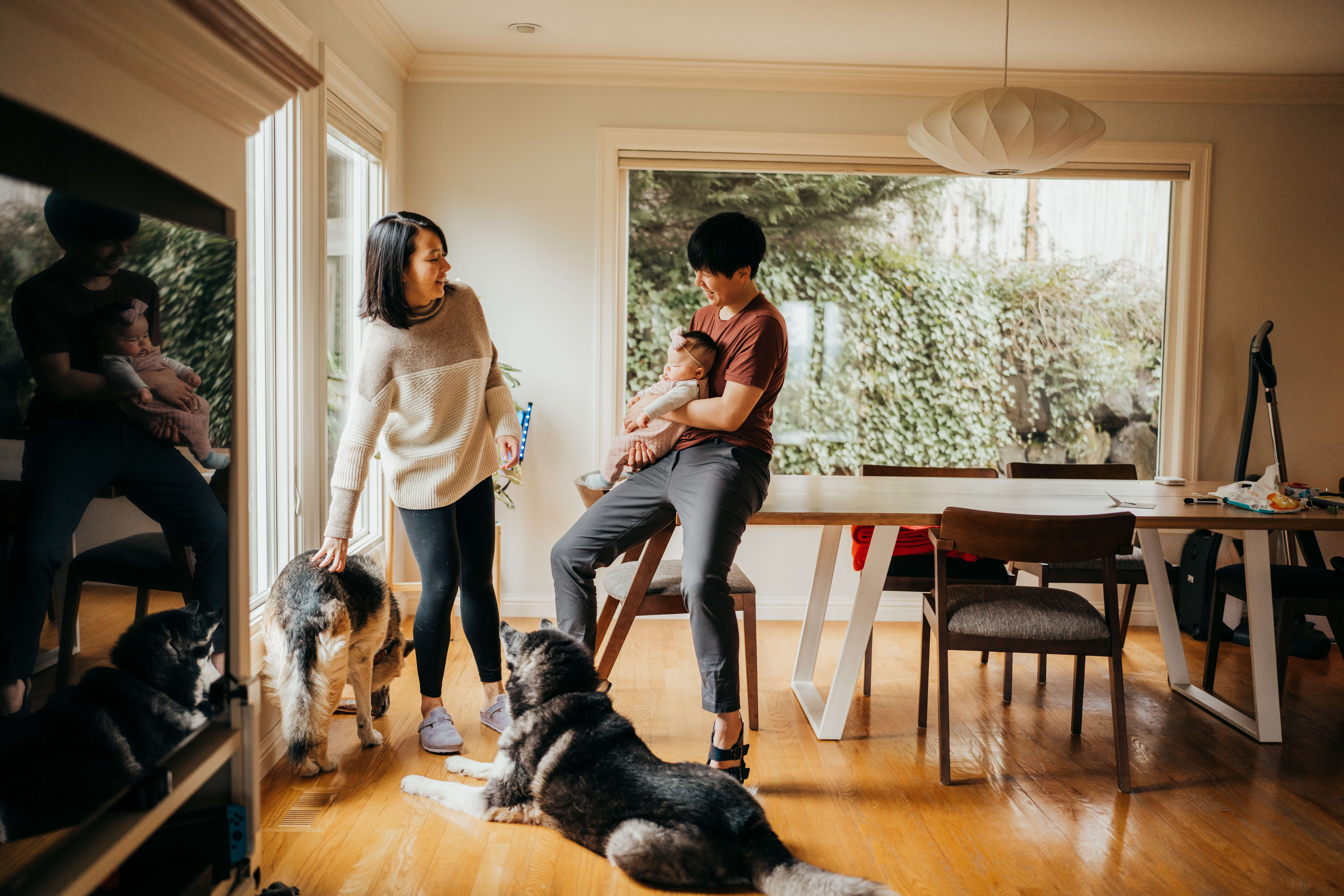 Happy new mom and dad relax in their dining room with two huskies and newborn after visiting seattle children's fetal center