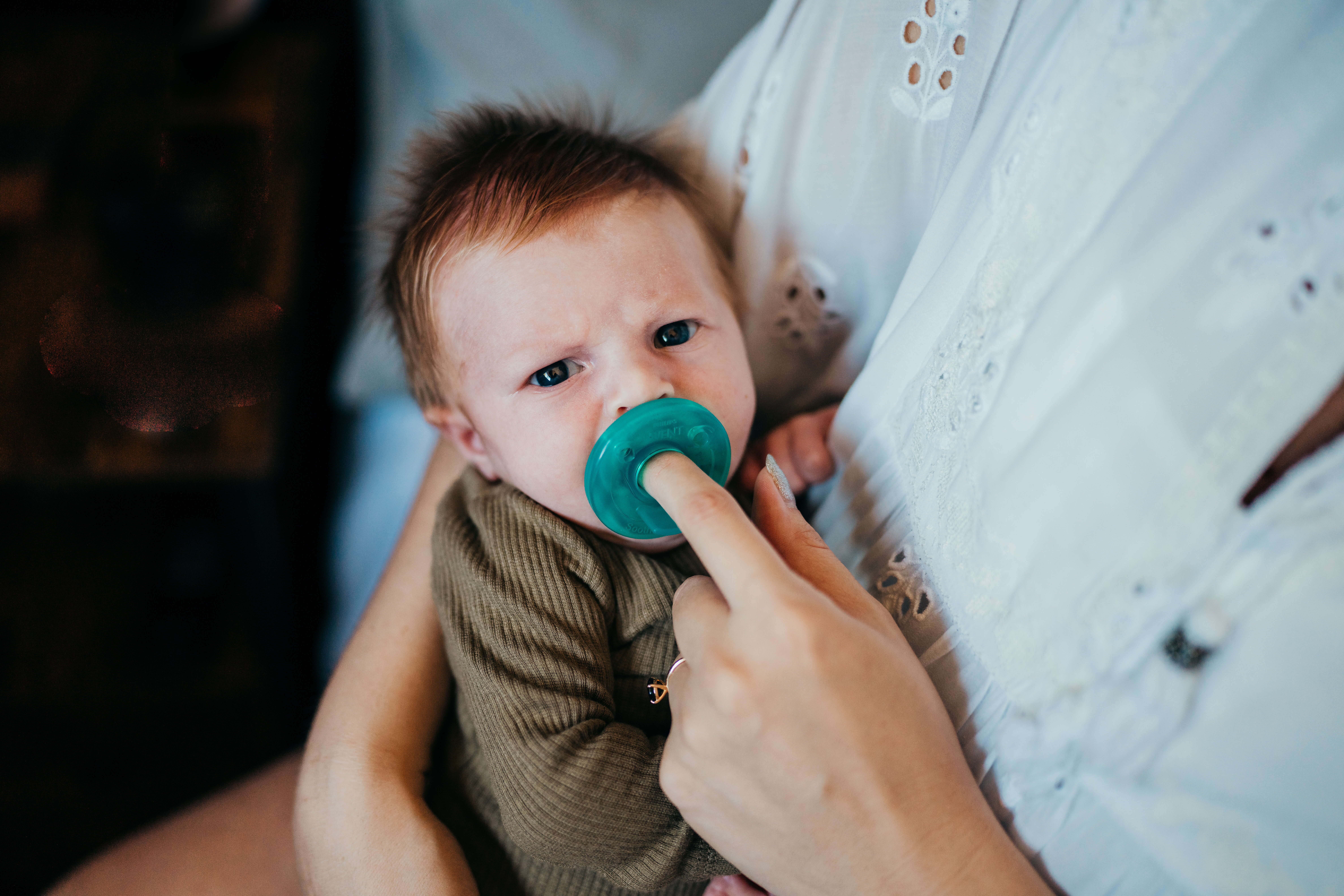 A mom holds a binky in a newborn baby's mouth while laying against her chest after meeting thresholds seattle