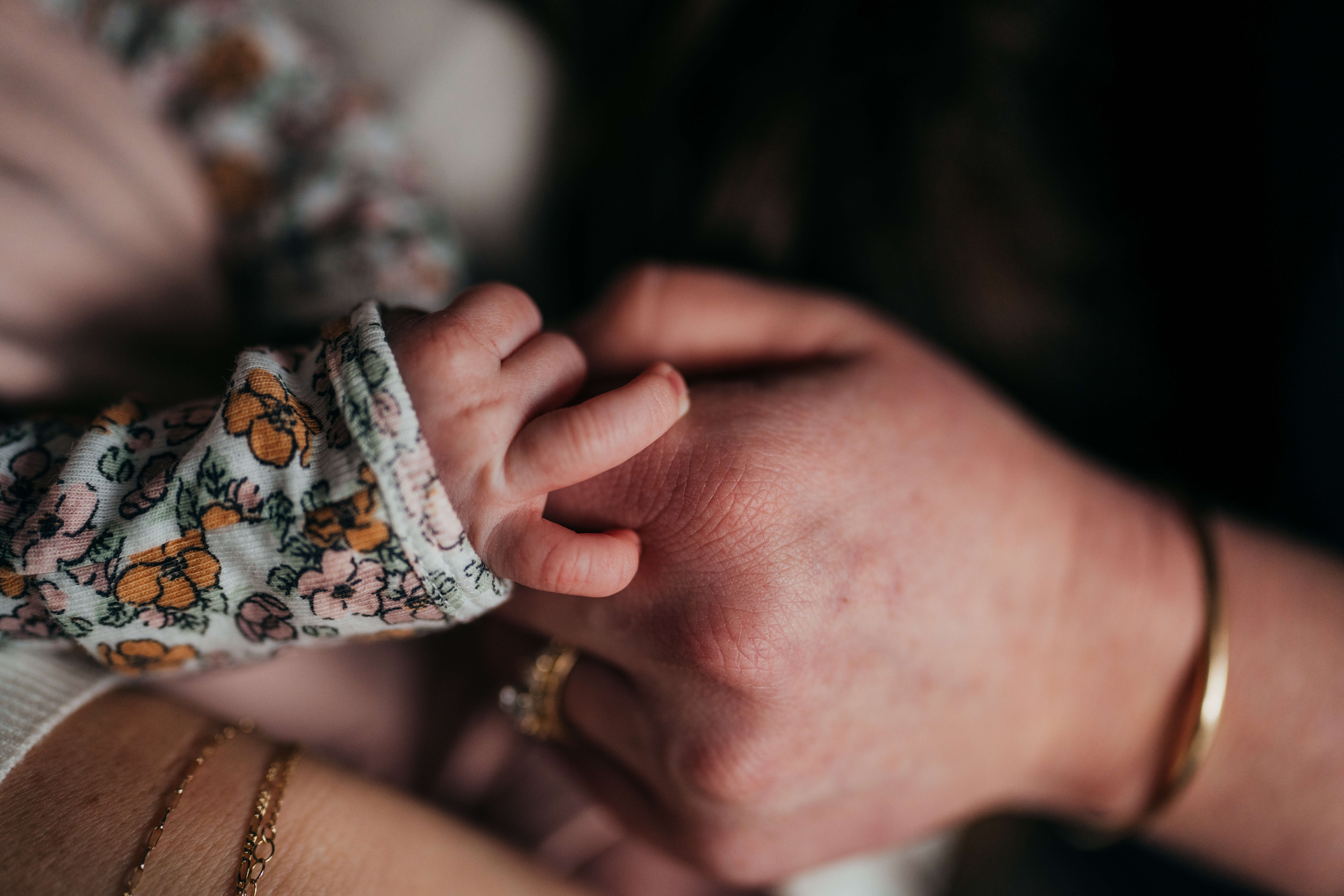 Details of a newborn baby's hand holding mom's finger